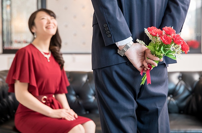 女性に花を渡そうとしている男性の後ろ姿